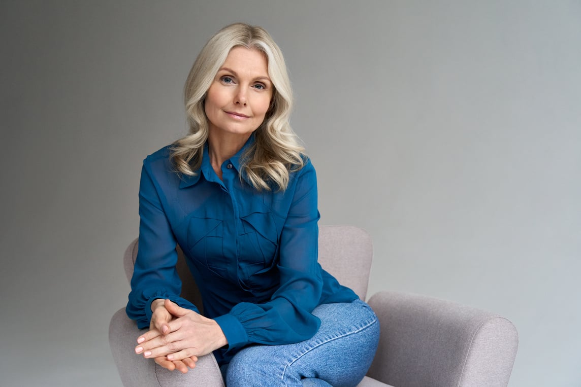 Middle Aged Female Psychotherapist Sitting in Chair Looking at Camera.
